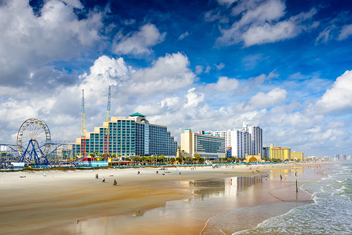 The cityscape of Daytona Beach with people sunbathing on sand